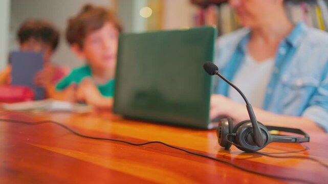 Remote teacher working from home using a headset and laptop for an online class with students, highlighting distance education and modern technology for e-learning