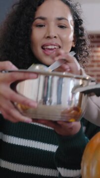 Vertical video: Guiding mom in green top with pot as child scooping pumpkin, dad holding in kitchen