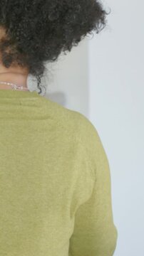 Vertical video: Shifting woman in green top turning at home near rail lowering arm holding phone