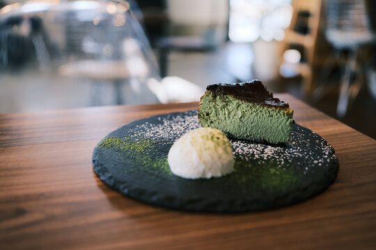 Matcha basque cheesecake with vanilla ice cream on a slate plate