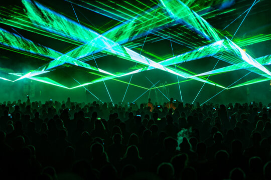 Geometric green laser network projected over spectators during night performance at Light Festival.