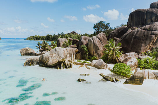 "La digue" island in Seychelles. Silver beach with granitic stone, and jungle. Man enjoying vacations on the beach and having fun with kayak. Aerial view shot with drone