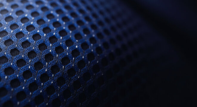 Close up of dark blue mesh fabric with hexagonal holes and white threads creating a textured background pattern