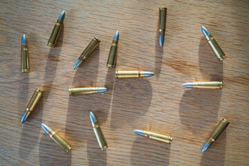 Custom reloaded 7.62x39mm rifle cartridges with unjacketed lead bullets scattered on a wooden table surface for shooting sports and hunting. © Dmitri