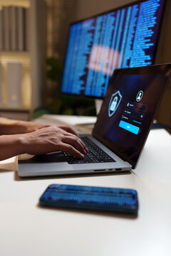 Cybersecurity professional accessing a secure login interface on a laptop, with digital code on a monitor, representing data protection and online privacy.