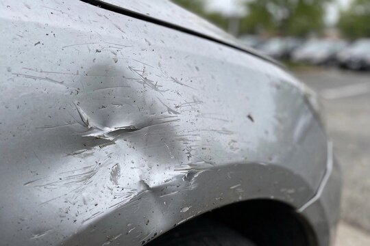 Close-up of scratched and dented car fender damage