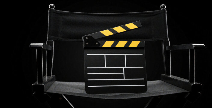 Black director chair with yellow clapper board on seat. Movie slate sits on empty cinema chair against dark background. Film production equipment for movie making, video studio gear, cinematography