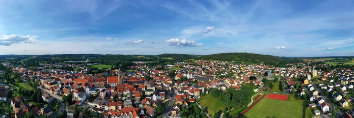 Malerische Luftaufnahme von Auerbach in der Oberpfalz mit der markanten Stadtpfarrkirche, traditionellen roten Dächern und idyllisch grüner Landschaft im Hintergrund unter blauem Himmel. © fotoping