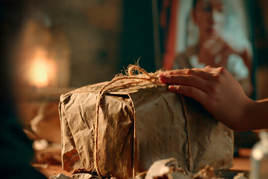 Close-up of hand on rustic gift box wrapped in brown paper.