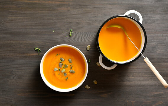 Delicious homemade creamy pumpkin soup on brown wooden background