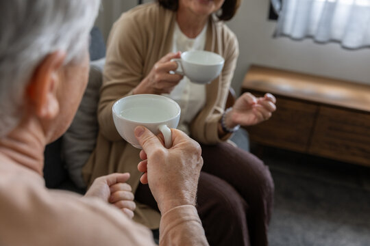 Older adults sharing tea in cozy living room, enjoying relaxed conversation together