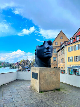 Centurione I bronze head sculpture by Igor Mitoraj beside the Regnitz River in Bamberg old town, Germany