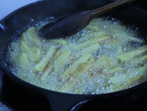 Close up with cast-iron pan cooking fries in pork fat