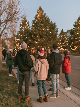 Group of People Gathering Outside Near Illuminated Christmas Trees in Winter