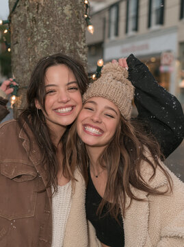 Two Smiling Young Women Friends Embracing Outdoors in Winter