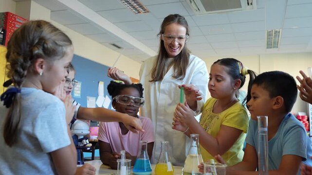 Diverse group of elementary school children with their teacher during a fun and interactive science lesson, learning about chemistry with colorful liquids