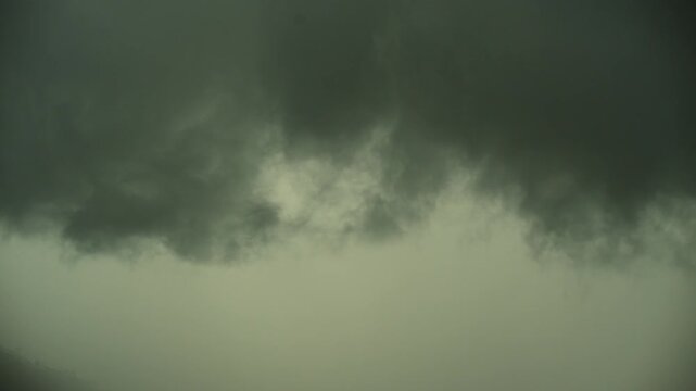 Dense dark monsoon storm clouds roll low across the sky above a Kathmandu Valley hillside in Nepal