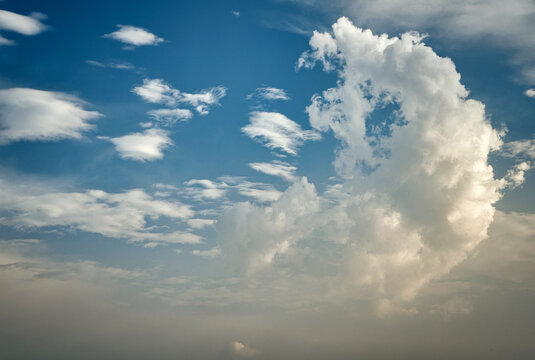 Dramatic clouds in a vibrant blue sky during a tranquil afternoon. A stunning fluffy white clouds against a bright blue sky, creating a peaceful atmosphere perfect for nature-themed projects.