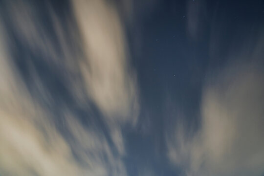Dramatic clouds swirling in the night sky with soft light effects. A mesmerizing view of clouds swirling in the night sky, creating a dramatic atmosphere with soft light effects and a sense of motion