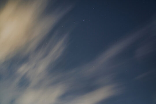 Dramatic long exposure clouds swirling in the night sky. A mesmerizing long exposure image capturing the movement of clouds against a dark night sky, evoking a sense of tranquility and wonder.