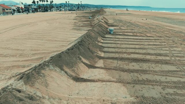 Aerial close up of long rows of sand banks and protective beach mounds shaped by heavy equipment to reduce coastal flooding risks.