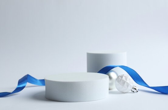Christmas composition with podiums, blue riboon and festive baubles on white background 