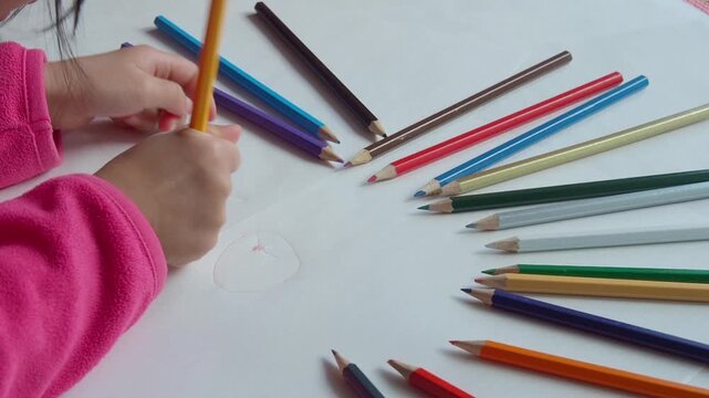 家のリビングでカラフルな色鉛筆で絵を描いている幼児の子供の姿