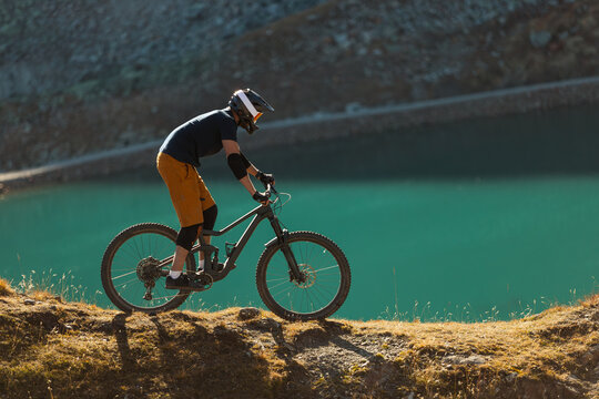 Mountain Biker Descending a Rocky Alpine Trail Above a Glacier