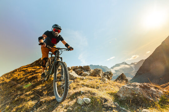 Mountain Biker Descending a Rocky Alpine Trail Above a Glacier