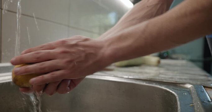 Close-up male hands wash rinse potatoes. 4K 10-bit