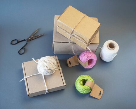 Cardboard boxes and packing twine; delivery concept. Cardboard boxes and packaging materials on a gray background; post office. Packer's workstation.