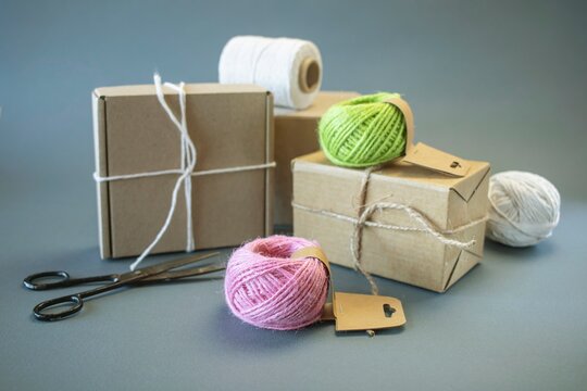 Cardboard boxes and packing twine; delivery concept. Cardboard boxes and packaging materials on a gray background; post office. Packer's workstation.