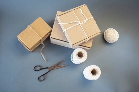 Cardboard boxes and packing twine; delivery concept. Cardboard boxes and packaging materials on a gray background; post office. Packer's workstation.