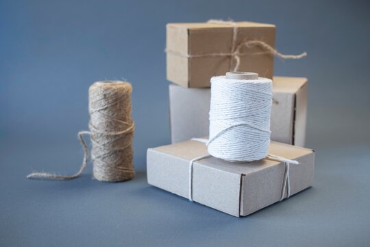 Cardboard boxes and packing twine; delivery concept. Cardboard boxes and packaging materials on a gray background; post office. Packer's workstation.