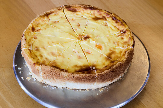 Traditional German cheesecake or baked quark cake with mandarin oranges, sliced into portions on a metal platter. Homemade round sweet dessert for a catering buffet close up.