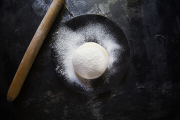 The head chef poses in the kitchen, set against a dark floor, with white dough and flour creating a striking contrast. © myCan