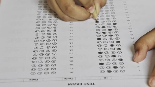 People filling out multiple choice test sheet with pencil