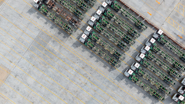 Aerial view port terminal trucks and chassis trailers lined up in logistic yard, Terminal tractors parked with bombcart trailers at container port terminal.