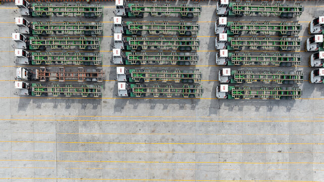 Aerial view port terminal trucks and chassis trailers lined up in logistic yard, Terminal tractors parked with bombcart trailers at container port terminal.