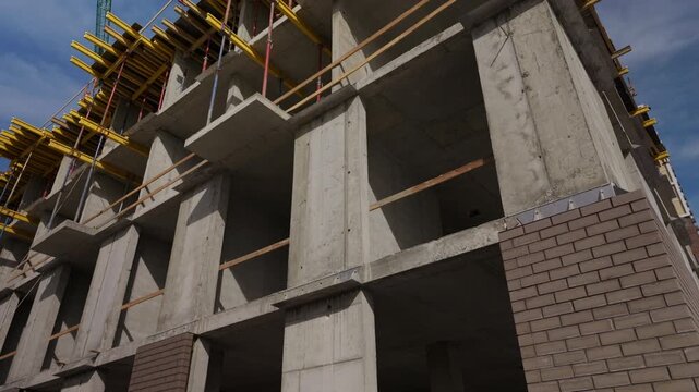 Unfinished multistory concrete building with brick facade and floor formwork
