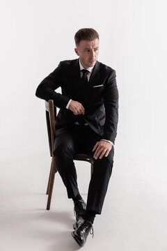 Classy middle aged man sitting on a wooden chair