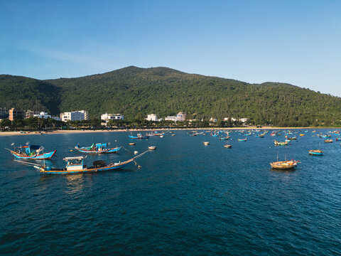fishing boats and round coracle basket boats floating in sea bay near green mountain coastline in Danang Vietnam, aerial drone view