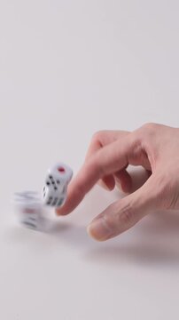 Finger flicking a vertical dice tower to tip it over on plain white background