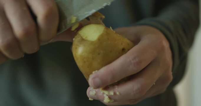 Close-up male hands peel boiled potato with knife. 4K 10-bit