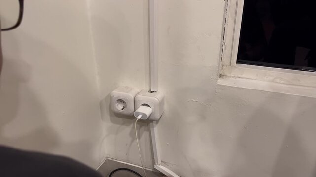people plugging smartphone charger to electric wall socket