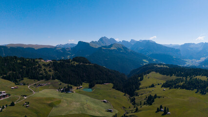 Fototapeta premium View of beautiful landscape in the Alps with fresh green meadows in the background on a sunny day with blue sky and clouds in summertime. Alpe de Siusi, Dolomite Alps