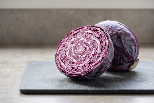 Purple cabbage cut in half on a grey board