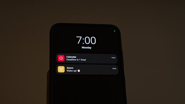 Monday 7:00 on a smartphone lock screen as notifications arrive: a calendar reminder of a deadline in 1 hour and an alarm saying wake up. It captures a stressful Monday morning, oversleeping, time pr
