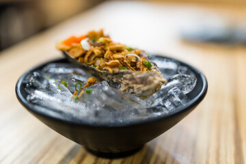 Fresh oyster served in thai style seafood with chili paste and fried onion on ice © Dontree