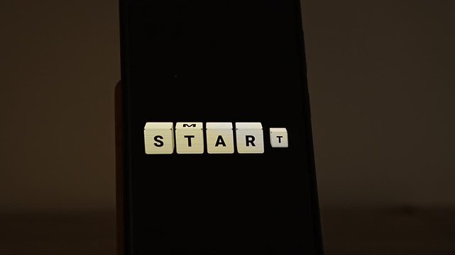 Cream letter cubes on a smartphone in a dim room spell START, then the second cube flips so the word becomes SMART. A clever wordplay for SMART goals, a smart start, goal setting frameworks and wise 